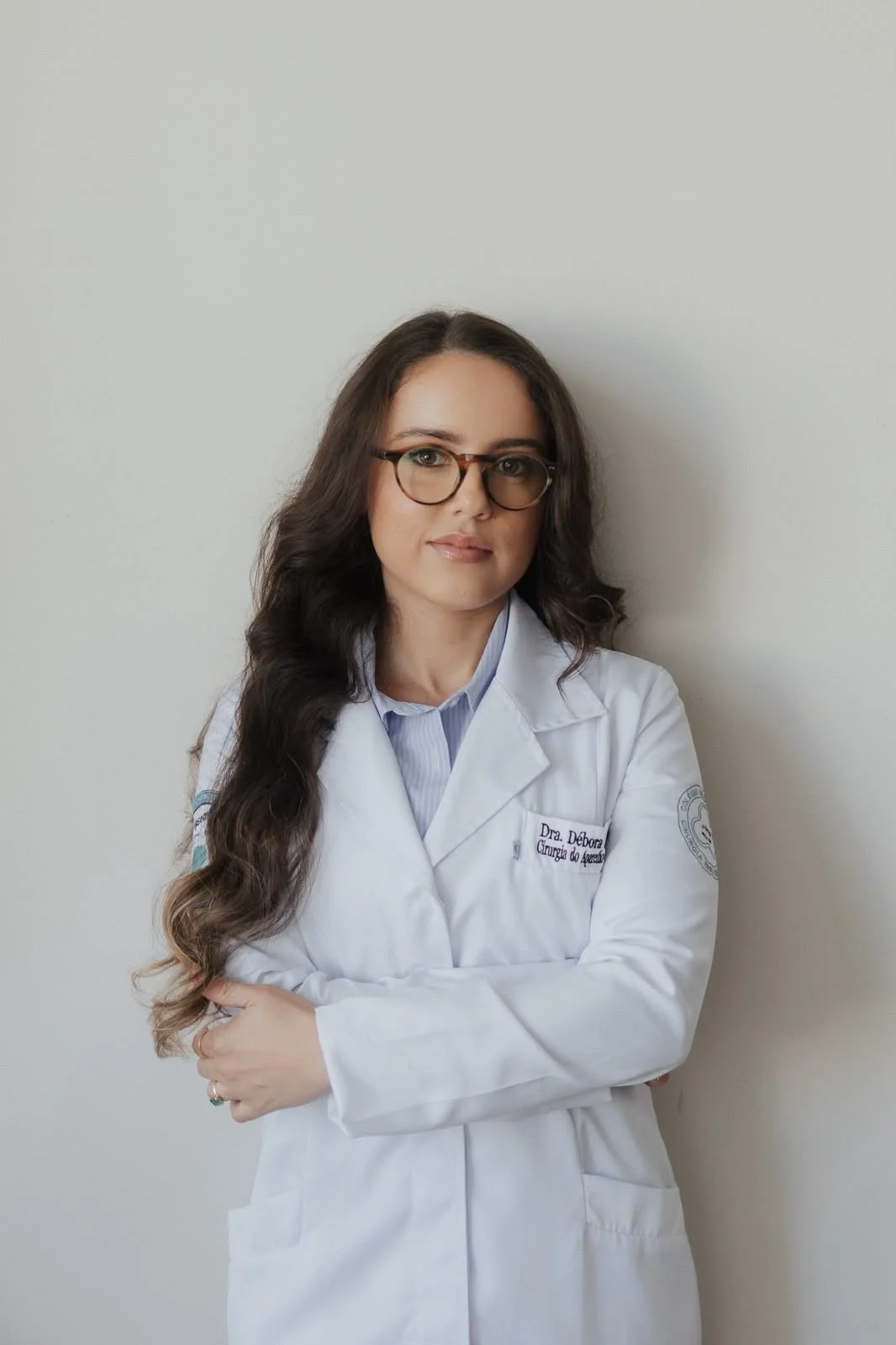 Dra. Débora Sampaio, cirurgiã do aparelho digestivo, com jaleco branco e braços cruzados